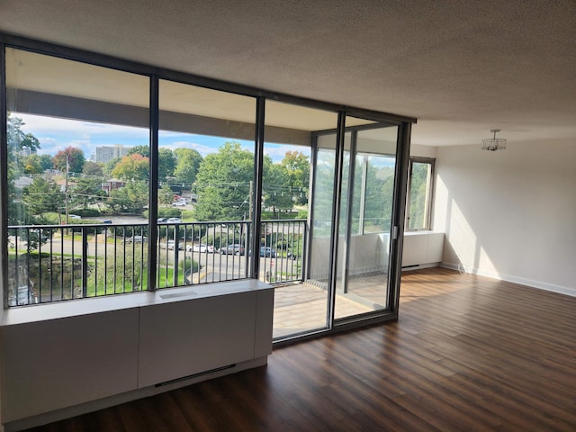 doorway featuring floor to ceiling windows, wood finished floors, a textured ceiling, and baseboards