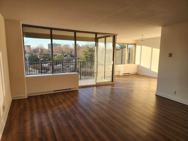 empty room with baseboards, wood finished floors, and floor to ceiling windows