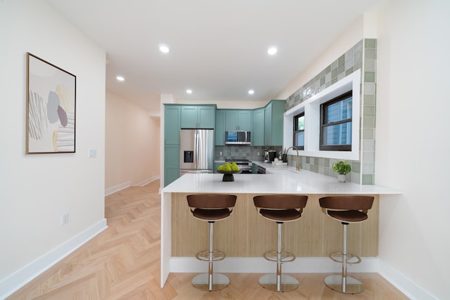 247 Harrison Ave Unit 1, Jersey City, NJ 07304 - kitchen featuring appliances with stainless steel finishes, a peninsula, a breakfast bar area, light countertops, and recessed lighting