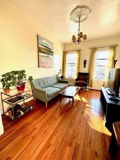 living room featuring plenty of natural light, a chandelier, a textured ceiling, and wood-type flooring