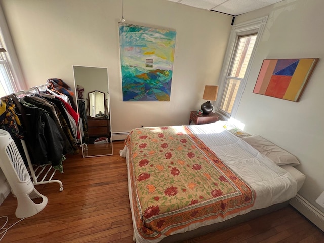 bedroom with baseboard heating and dark wood-type flooring