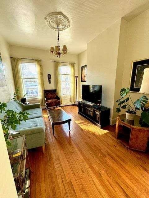 living room with hardwood / wood-style floors, a healthy amount of sunlight, a textured ceiling, and an inviting chandelier