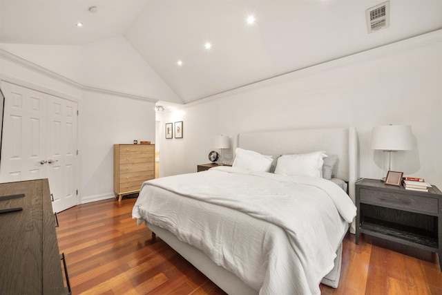 bedroom featuring high vaulted ceiling, wood finished floors, and visible vents