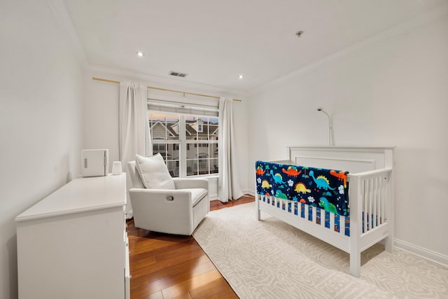 bedroom with hardwood / wood-style flooring, recessed lighting, visible vents, baseboards, and crown molding