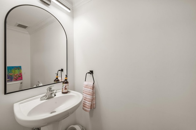 bathroom featuring crown molding, visible vents, and a sink