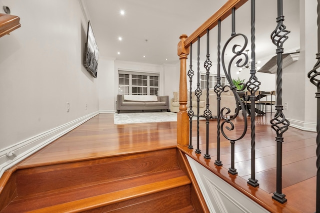 stairs with crown molding, recessed lighting, wood finished floors, and baseboards