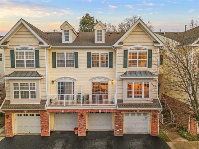 multi unit property with driveway, a garage, and brick siding