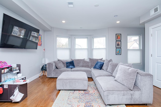 living area with recessed lighting, visible vents, baseboards, and light wood finished floors