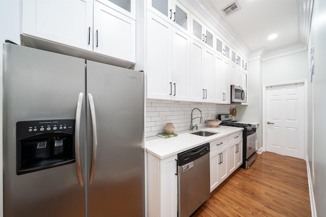 kitchen with sink, appliances with stainless steel finishes, backsplash, hardwood / wood-style floors, and white cabinets