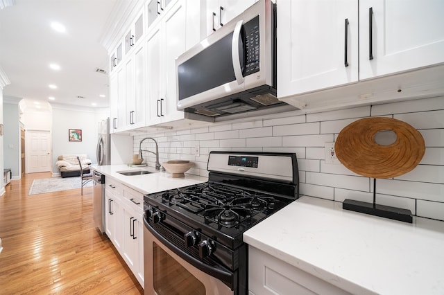 kitchen featuring sink, backsplash, stainless steel appliances, ornamental molding, and white cabinets