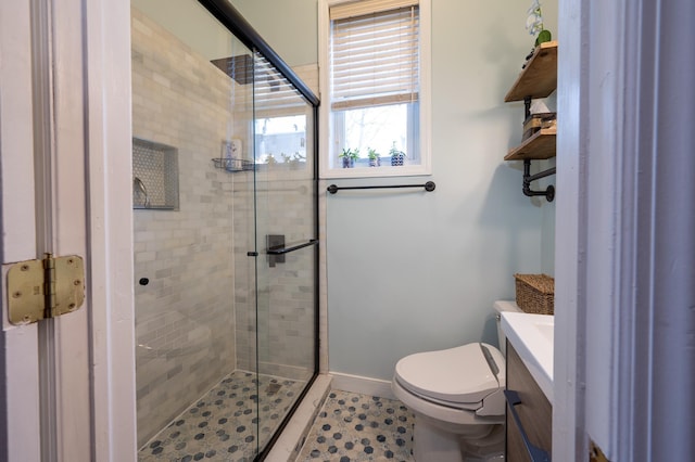 bathroom featuring vanity, a shower with shower door, and toilet