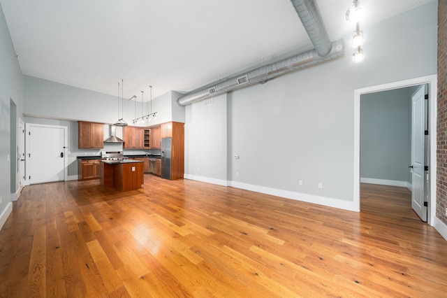 interior space with light wood finished floors, a high ceiling, and baseboards