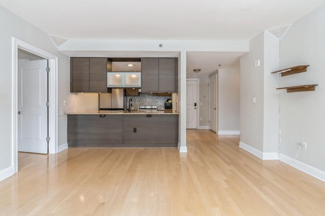 kitchen featuring sink, stainless steel fridge, backsplash, dark brown cabinets, and light hardwood / wood-style floors