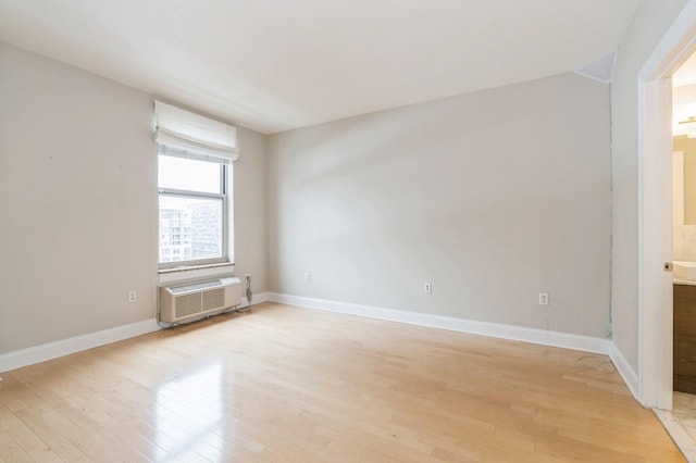 unfurnished room featuring an AC wall unit and light wood-type flooring