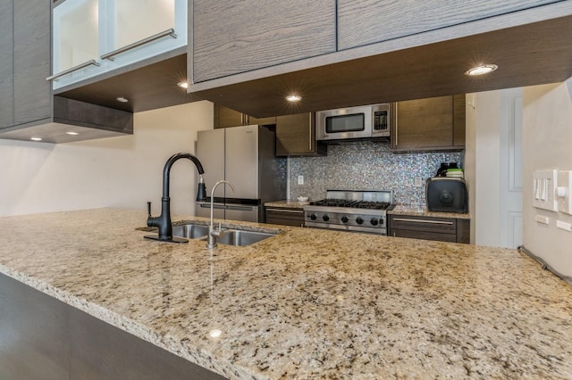 kitchen featuring sink, tasteful backsplash, kitchen peninsula, stainless steel appliances, and light stone countertops