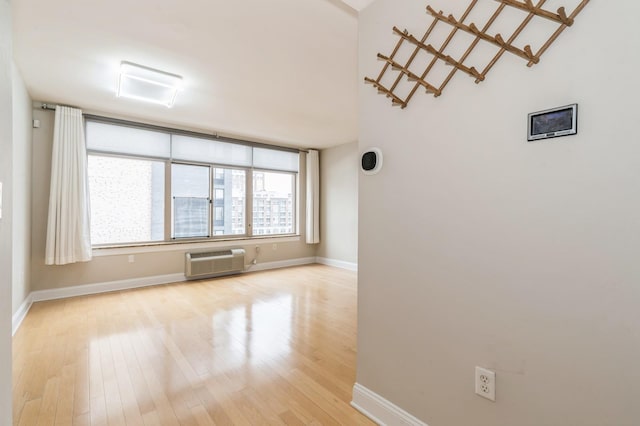 empty room featuring a wall mounted AC and light wood-type flooring