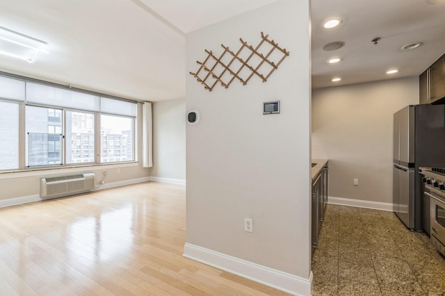 kitchen featuring stainless steel fridge, a wall unit AC, and light wood-type flooring