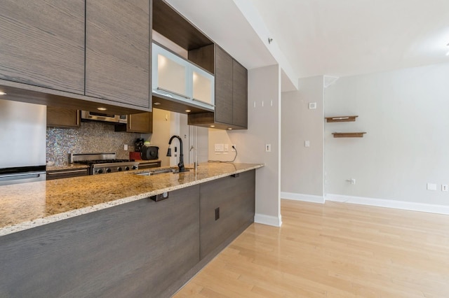 kitchen featuring refrigerator, stove, light stone counters, tasteful backsplash, and light hardwood / wood-style floors