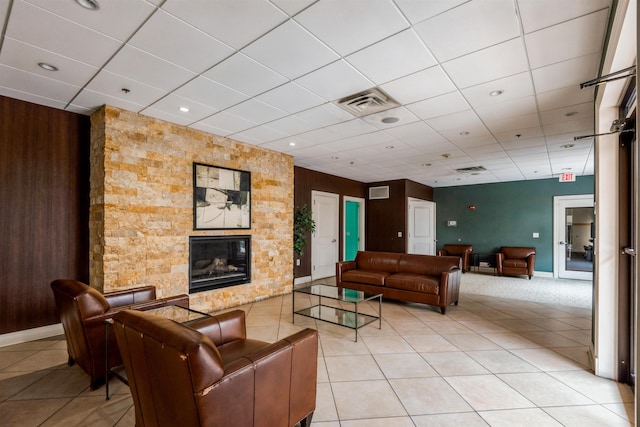 living room with wooden walls, tile patterned floors, a fireplace, and a drop ceiling