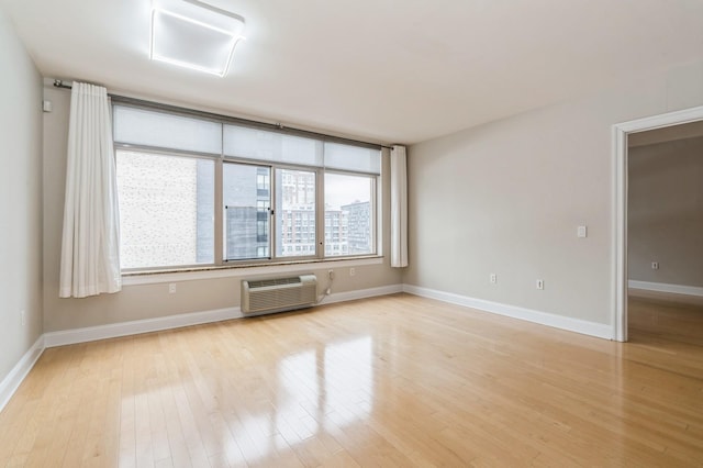 spare room with a wall mounted AC and light wood-type flooring