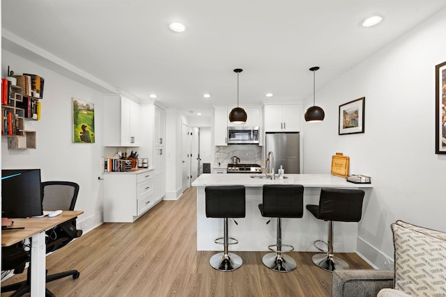 121 Coles St Unit 1, Jersey City, NJ 07306 - kitchen with stainless steel appliances, a peninsula, a kitchen bar, white cabinetry, and light wood-type flooring