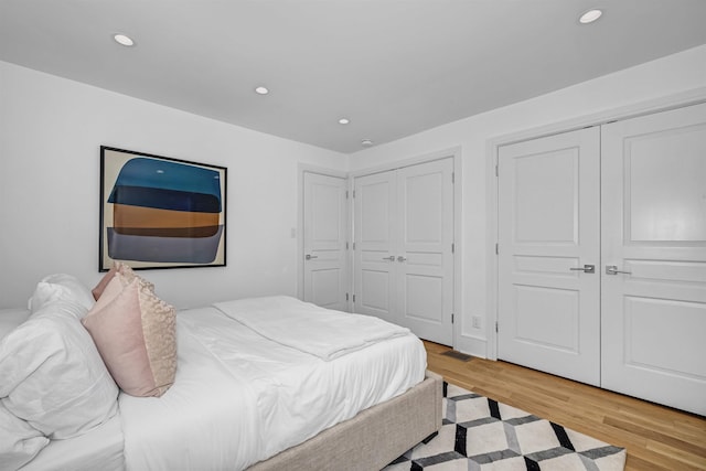 bedroom with multiple closets and light hardwood / wood-style flooring