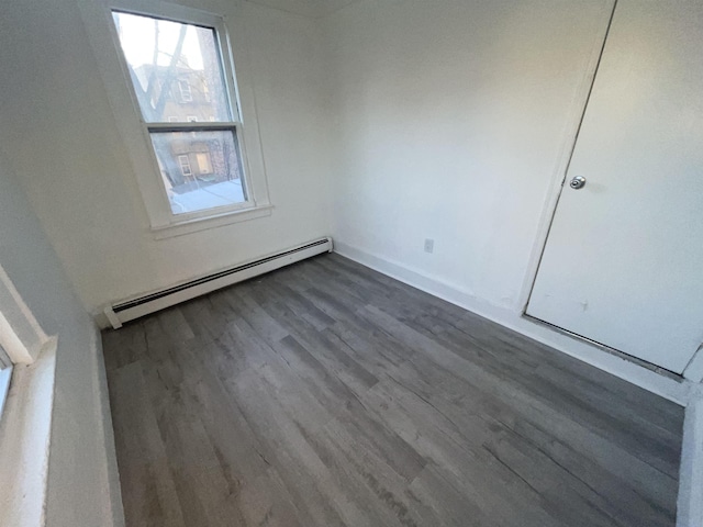 unfurnished room featuring a baseboard heating unit and dark wood-style flooring