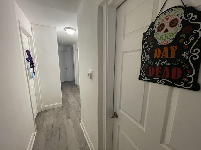 hall featuring light wood-style flooring and baseboards