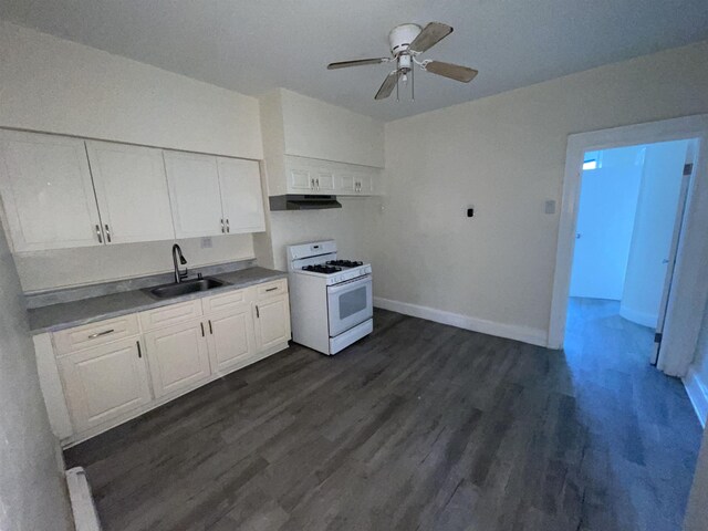 kitchen with a sink, under cabinet range hood, white gas range, and dark wood finished floors