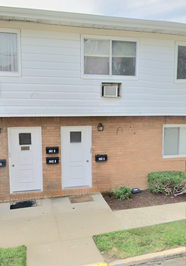 view of exterior entry featuring a wall unit AC and brick siding