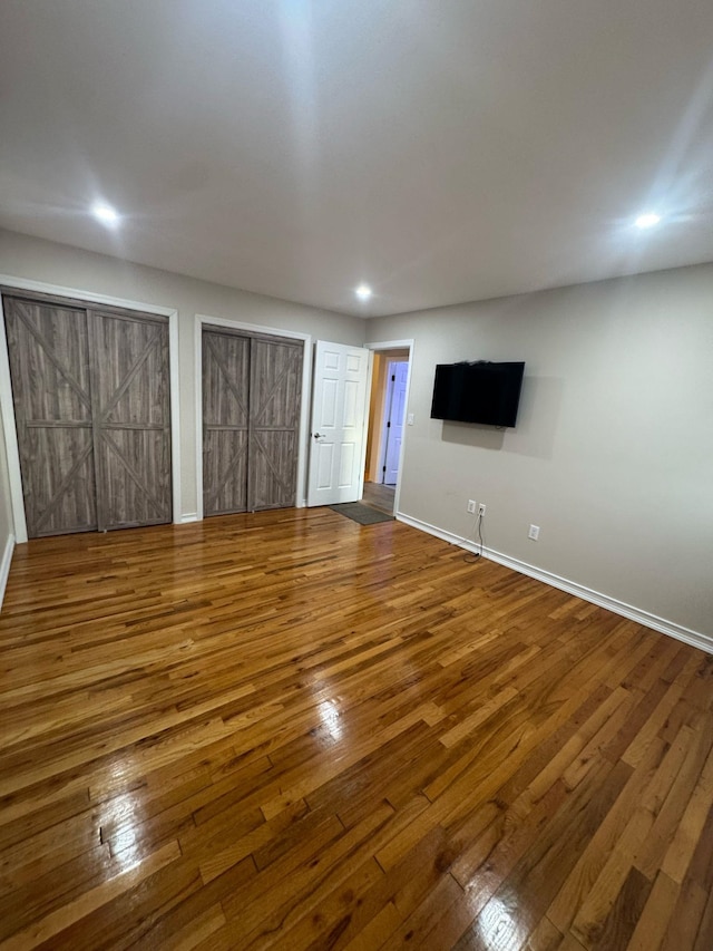 unfurnished living room with recessed lighting, wood-type flooring, and baseboards