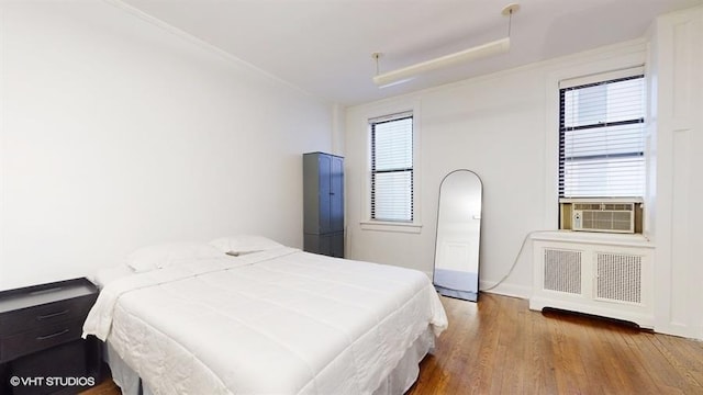 bedroom with radiator, cooling unit, and hardwood / wood-style flooring