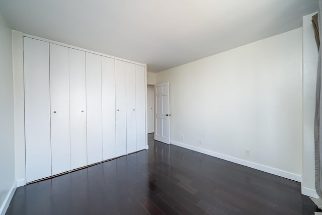 135 Montgomery St Unit 21H, Jersey City, NJ 07302 - unfurnished bedroom with dark wood-type flooring, baseboards, and a closet