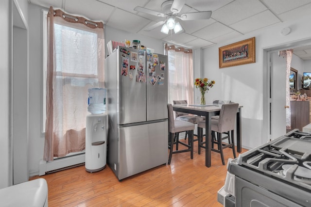 9 E 15th St, Bayonne, NJ 07002 - kitchen featuring stainless steel appliances, a baseboard heating unit, a ceiling fan, light wood finished floors, and a paneled ceiling
