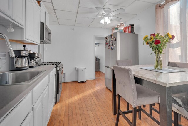 9 E 15th St, Bayonne, NJ 07002 - kitchen featuring stainless steel appliances, white cabinetry, light countertops, and a paneled ceiling