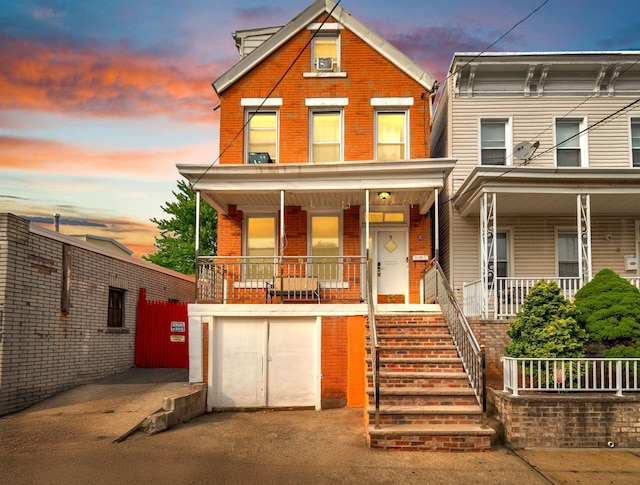 9 E 15th St, Bayonne, NJ 07002 - view of front of home featuring covered porch, brick siding, stairs, asphalt driveway, and a garage