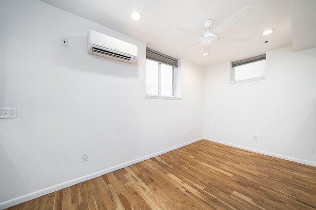 spare room with a wall unit AC, light wood-style flooring, recessed lighting, a ceiling fan, and baseboards