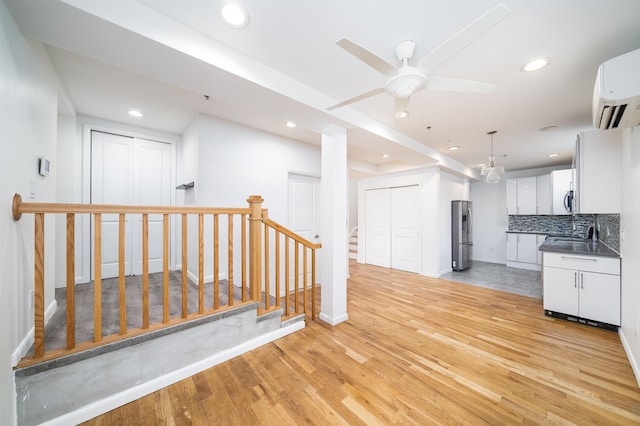 interior space featuring an AC wall unit, light wood finished floors, freestanding refrigerator, and decorative backsplash