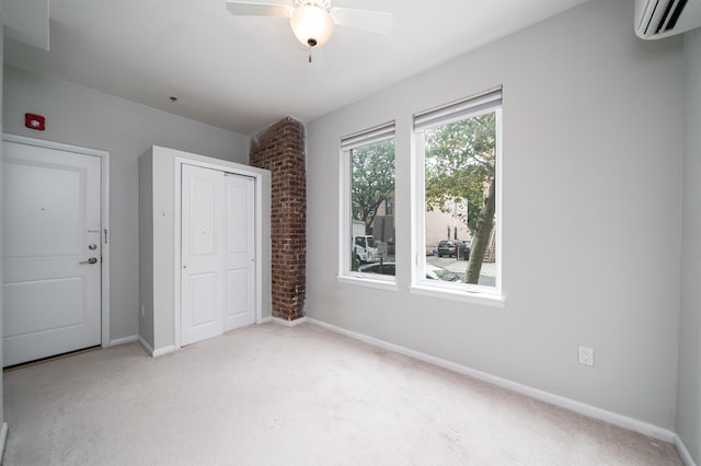 unfurnished bedroom with light carpet, a ceiling fan, baseboards, a closet, and a wall mounted air conditioner