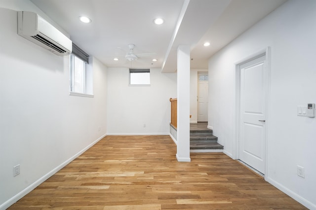 basement featuring recessed lighting, a wall unit AC, light wood-style flooring, and baseboards