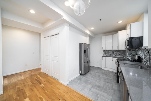 kitchen with tasteful backsplash, baseboards, white cabinets, stainless steel appliances, and recessed lighting