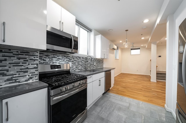 kitchen with dark countertops, stainless steel appliances, a wall unit AC, and a sink