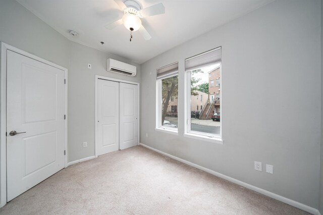 unfurnished bedroom featuring a closet, a ceiling fan, carpet flooring, a wall mounted air conditioner, and baseboards