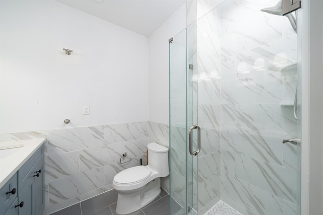 bathroom with a marble finish shower, toilet, tile walls, and vanity