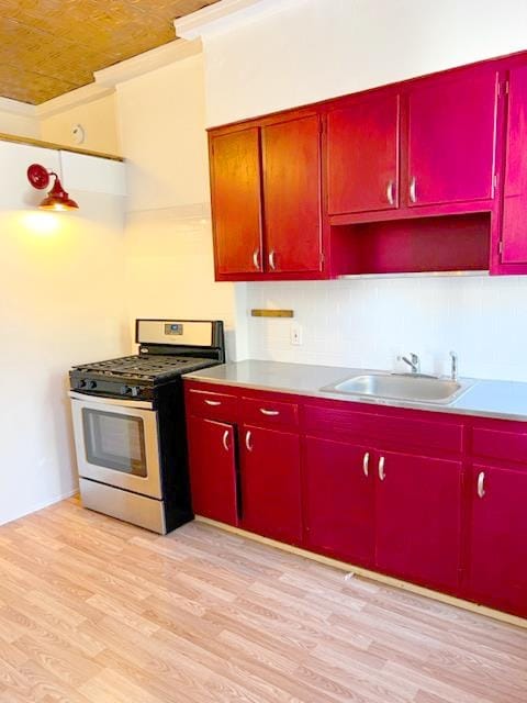 kitchen featuring range with gas stovetop, light wood-type flooring, and sink