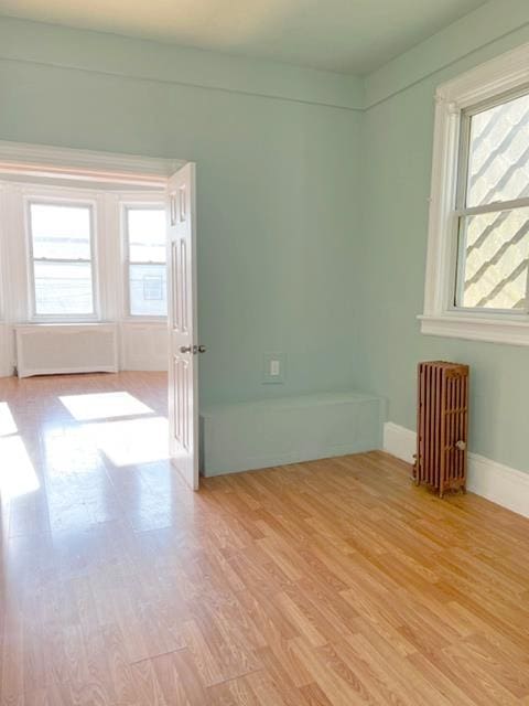 unfurnished room featuring light hardwood / wood-style floors and radiator heating unit