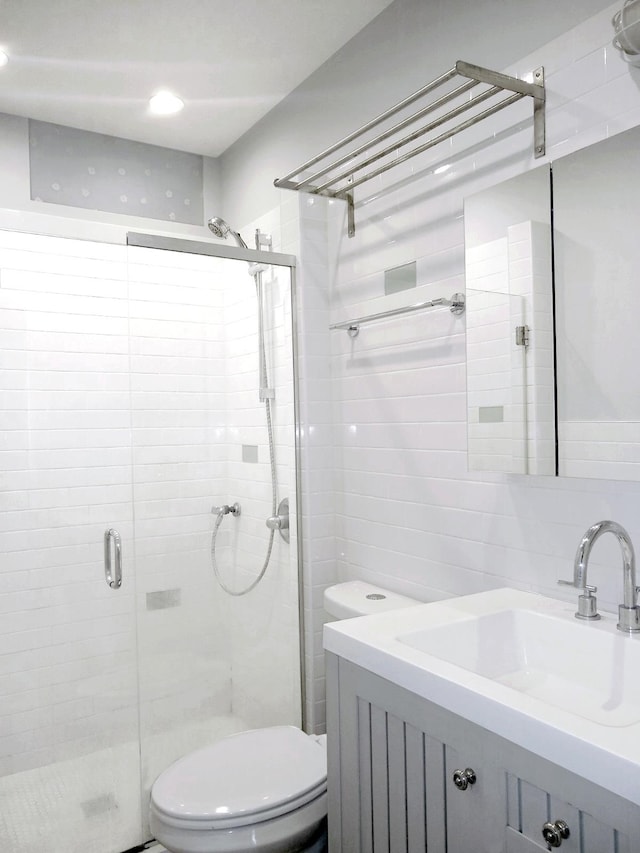 bathroom featuring a shower with door, vanity, and toilet