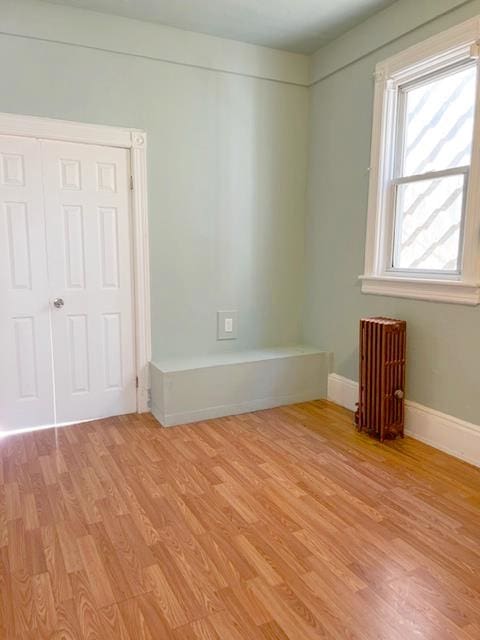 unfurnished room featuring radiator heating unit and light hardwood / wood-style flooring