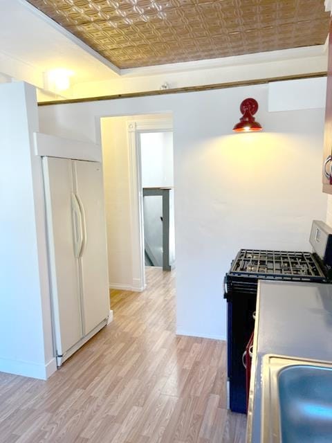 kitchen with stainless steel electric range, light wood-type flooring, brick ceiling, and white fridge