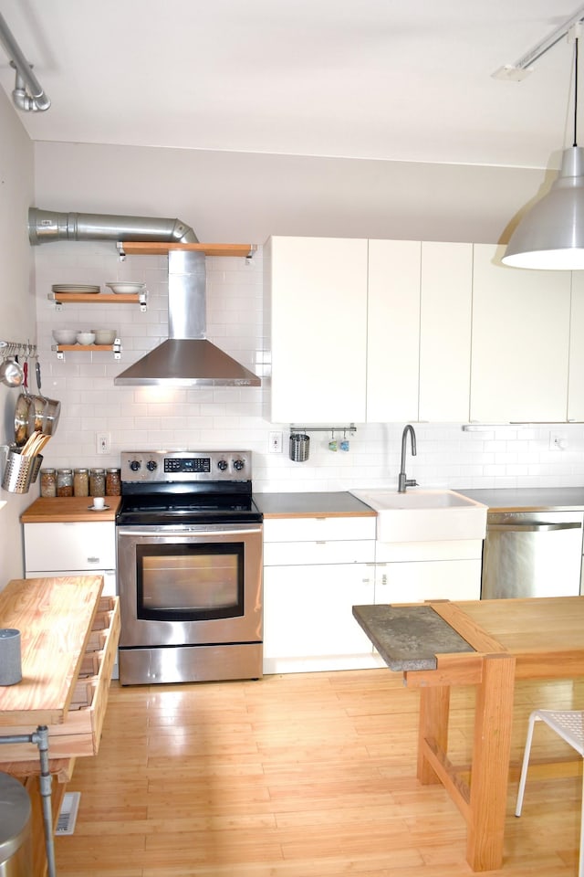 kitchen with stainless steel appliances, wall chimney exhaust hood, sink, tasteful backsplash, and white cabinetry